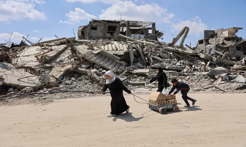 DISPLACED Palestinians carry boxes in a cart past the rubble of destroyed buildings at the Jabalia refugee camp, in Gaza Strip.&mdash;AFP