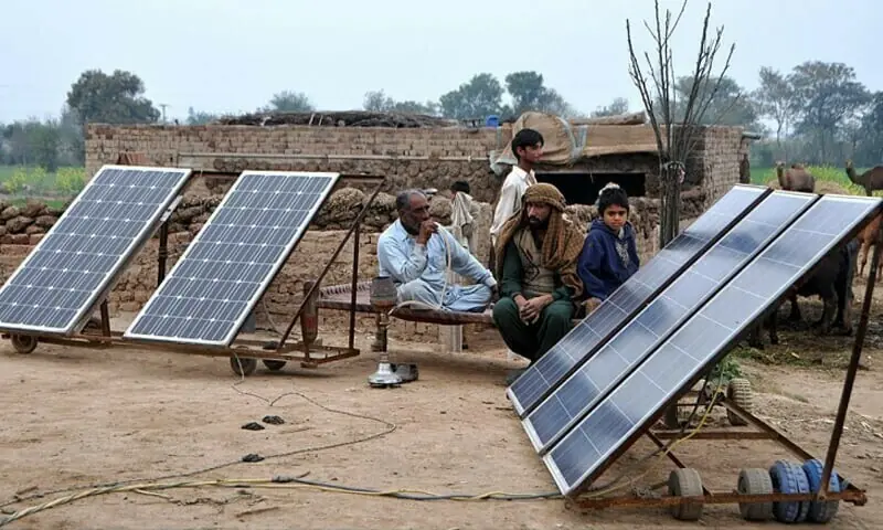 Villagers relax on a farm outside Sheikhupura next to their panels. &mdash;APP /File photo