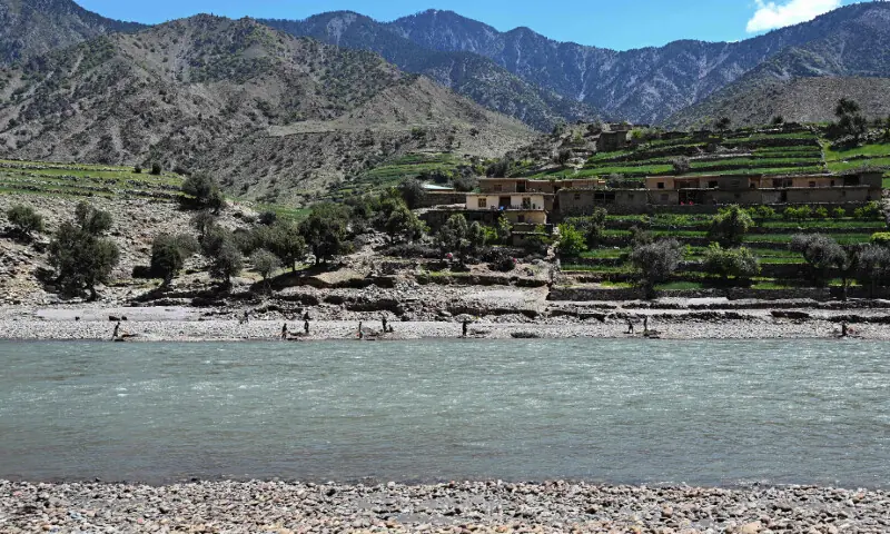 This photograph taken on April 13, 2026 shows Afghan men drawing water from Kunar river to sift through excavated mountainside stones in search of gold nuggets near mud-brick houses at the Kharwalu area of Naray district, Kunar province. &mdash; AFP