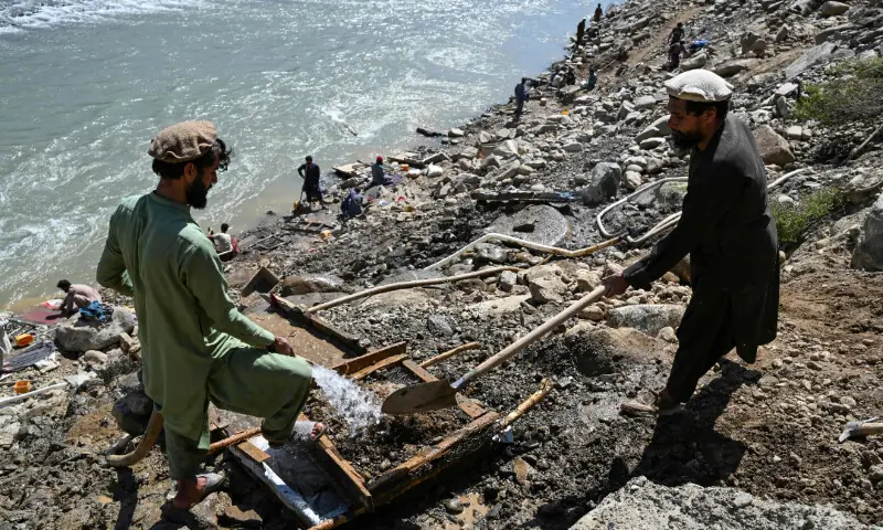 This photograph taken on April 13, 2026 shows an Afghan man pouring water over a seive as he sifts through mountainside stones in search of gold nuggets along the Kunar river in the Song area of Ghaziabad district, Kunar province.. &mdash; AFP