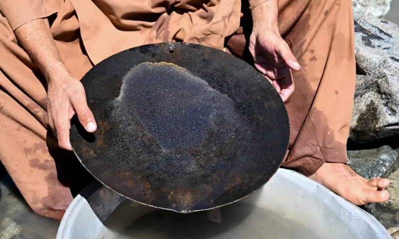 This photograph taken on April 13, 2026 shows an Afghan man scouring for gold using the traditional gold-panning technique, after sorting nuggets from mountainside stones excavated from the Kunar riverbed in the Kharwalu area of Naray district, Kunar province. &mdash; AFP