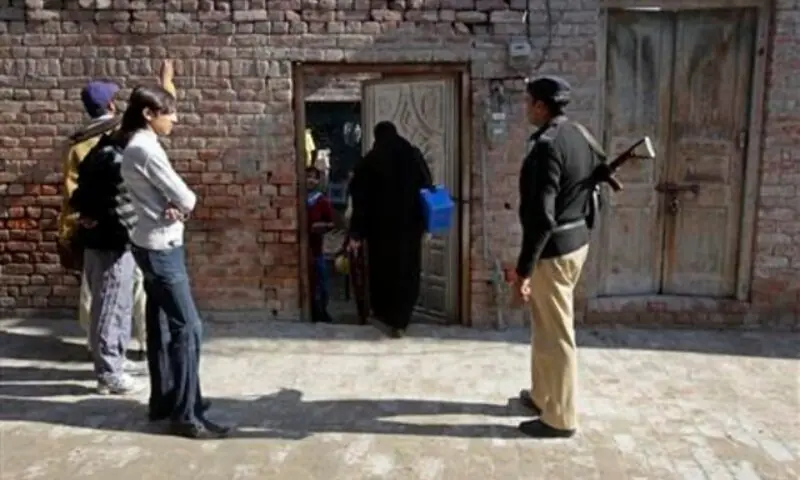 A policeman stands guard as female polio workers wait to give polio vaccine drops to children in Lahore Dec 20, 2012. —Reuters/File A policeman stands guard as female polio workers wait to give polio vaccine drops to children in Lahore Dec 20, 2012. —Reuters/File