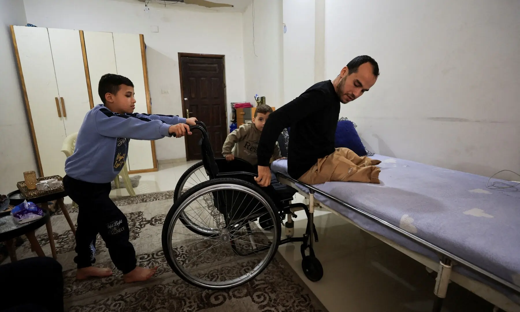 Palestinian amputee Omar Abu Ali, 34, who was injured in an Israeli strike, transfers from his wheelchair onto a bed at his home, in Gaza City on April 1, 2026. &mdash; Reuters