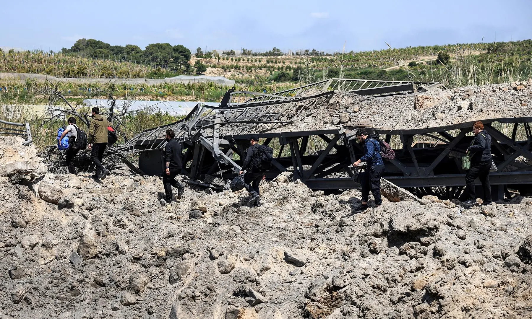 People cross on foot amid rubble after an Israeli strike severed the last remaining bridge linking southern Lebanon to the rest of the country, in Qasmiyeh, Lebanon on April 16, 2026. &mdash; Reuters