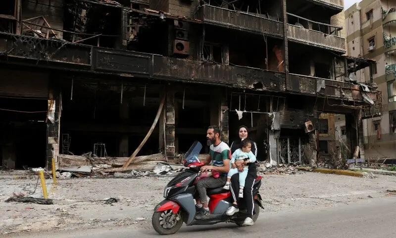People ride past damaged buildings as displaced people make their way to return to their homes after a 10-day ceasefire between Lebanon and Israel went into effect, at the southern suburbs of Beirut, Lebanon, April 17, 2026. &mdash;Reuters
