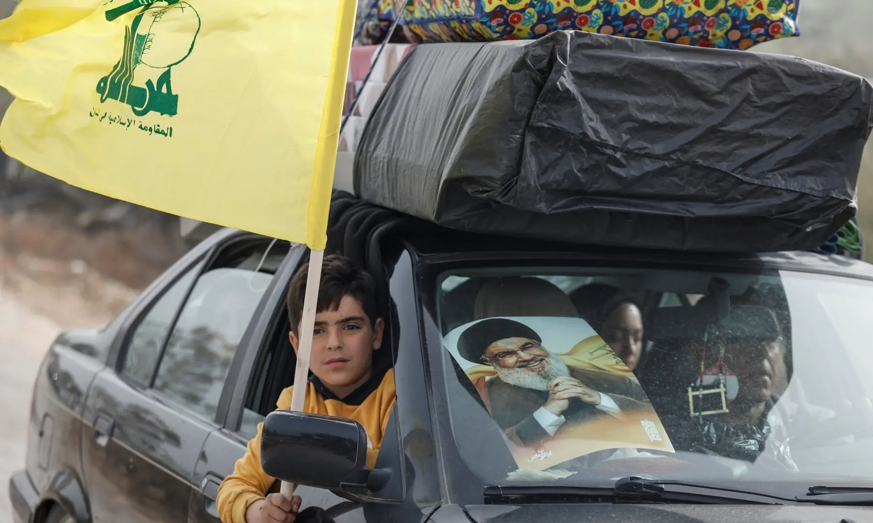 A child waves Hezbollah flag as  displaced people make their way back to their homes after crossing the bridge linking southern Lebanon to the rest of the country, following the ceasefire between Lebanon and Israel in Qasmiyeh, Lebanon on April 18, 2026. &mdash;Reuters