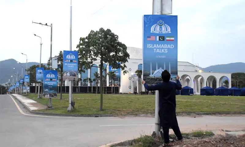 A man hangs a billboard on a pole outside Jinnah Convention Centre on Saturday ahead of possible second round of US-Iran talks in Islamabad. &mdash; Online