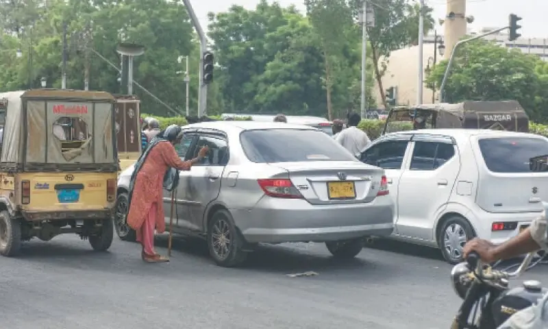 A BEGGAR seeks alms from a motorist at a traffic signal.&mdash;White Star/File