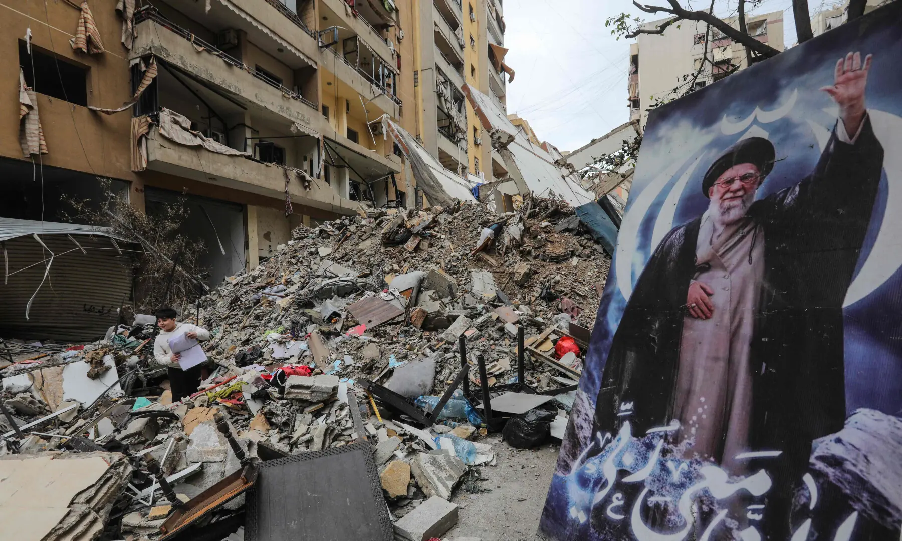 A boy stands amid the debris of a destroyed building next to a portrait of Iran’s slain supreme leader Ayatollah Ali Khamenei during a media tour organised by Hezbollah in the Haret Hreik area of Beirut’s southern suburbs on April 20, 2026.