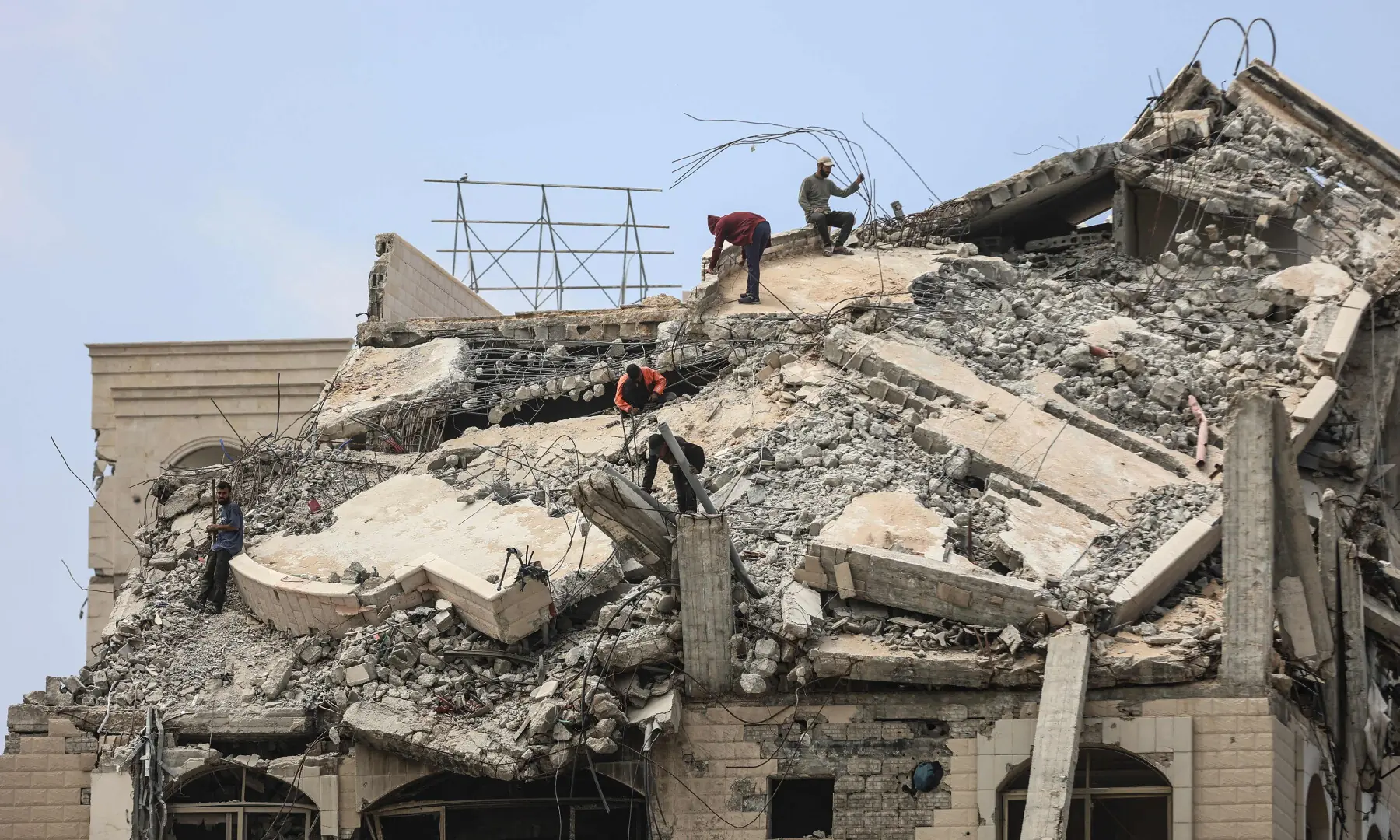 Palestinian men stand atop a heavily damaged building in Gaza City on April 20, 2026. &mdash; AFP