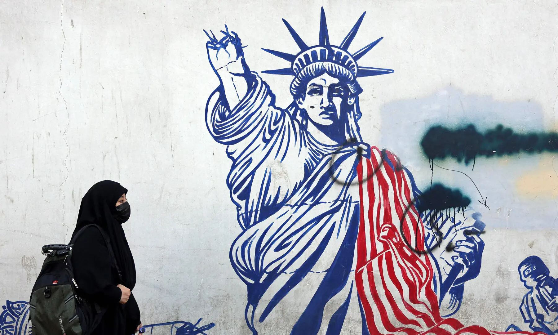 This photo taken on February 26, 2026 shows a veiled Iranian woman walking past an anti-US mural next to former US embassy in Tehran. &mdash; AFP/File