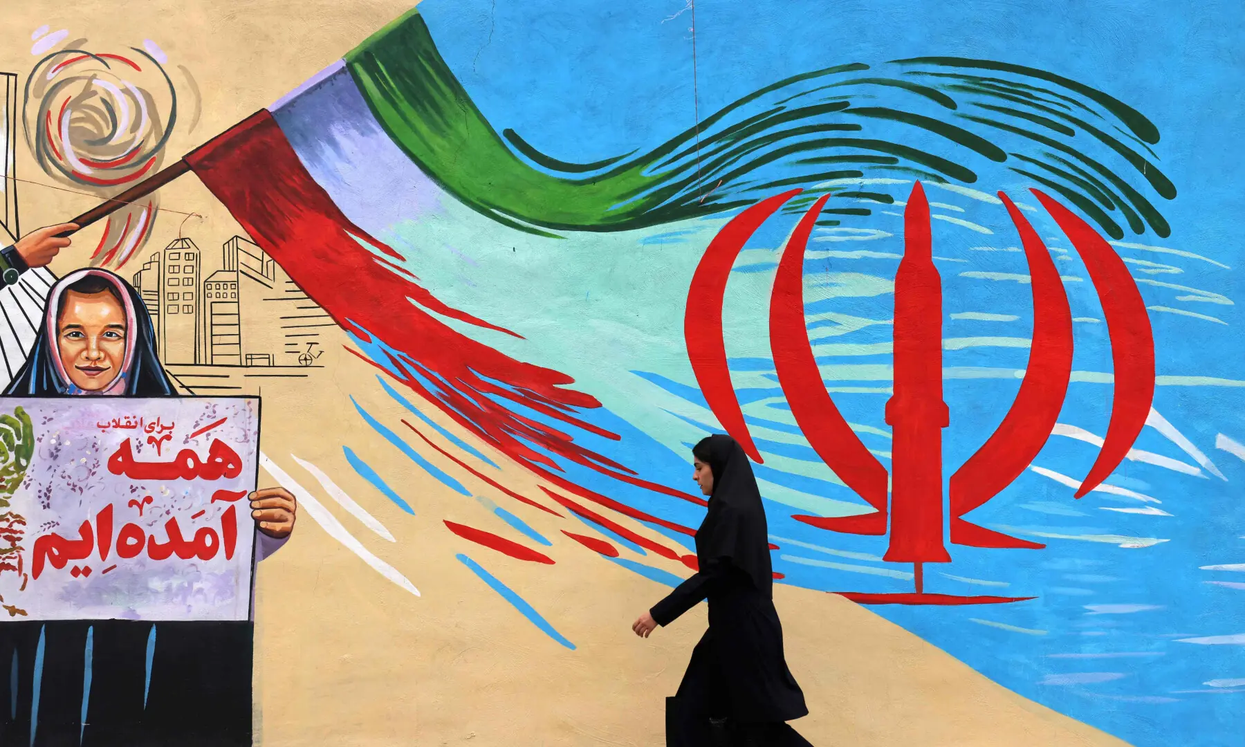 An Iranian woman walks past an anti-USA and anti-Israel mural, in Tehran on April 21 2026. &mdash; AFP