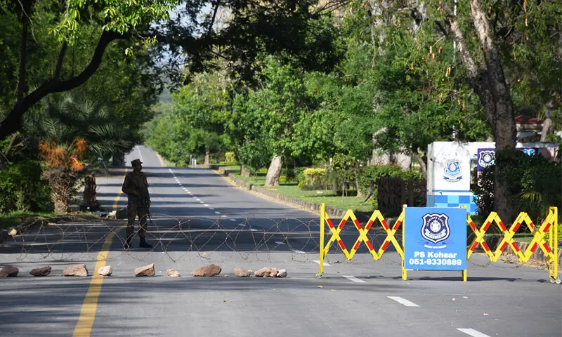 A security person stands guard on Margalla Road on Wednesday. The road has been sealed in connection with the expected second round of talks between the US and Iran. &mdash; Photo by Mohammad Asim