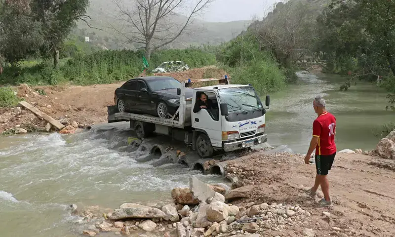 A tow truck crosses the Litani River through a makeshift bridge, after Israeli forces destroyed the previous one in the Lebanese village of Bedias.&mdash;AFP