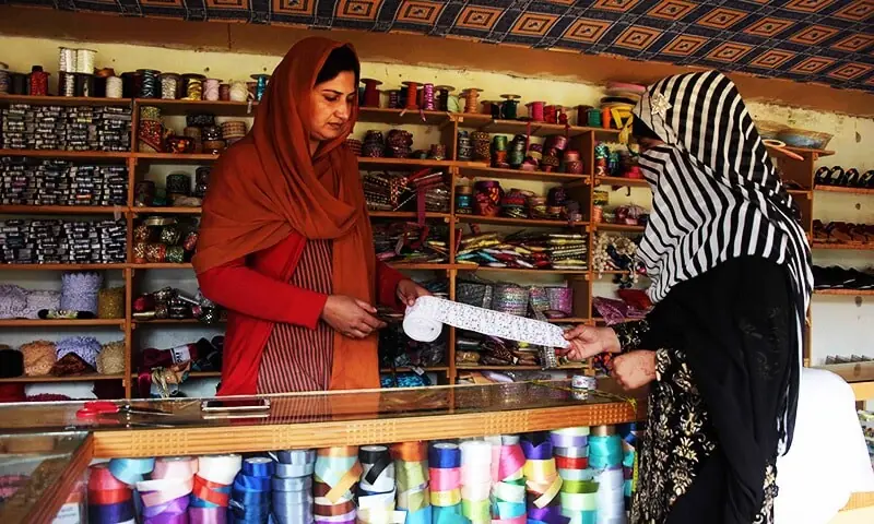 A woman sells border trim cloth to a customer at her shop in a women's market.— AFP/File A woman sells border trim cloth to a customer at her shop in a women's market.— AFP/File