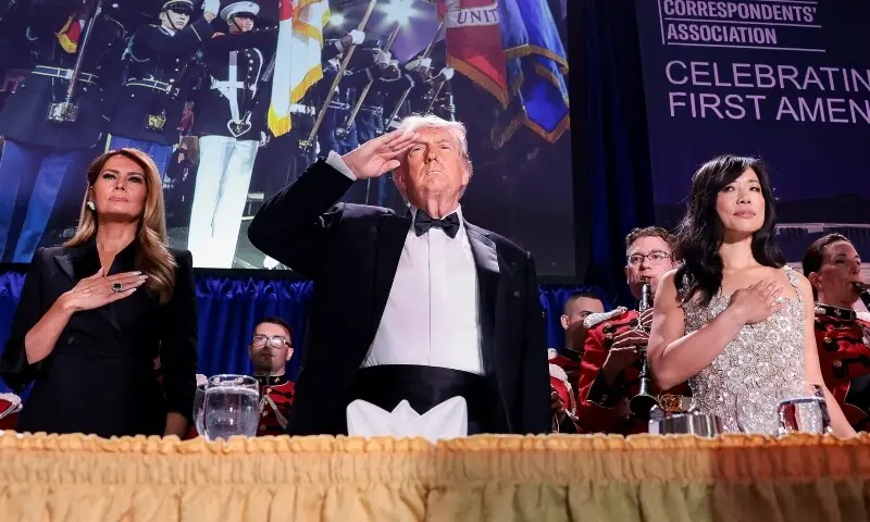 US President Donald Trump, with first lady Melania Trump and CBS News senior White House correspondent Weijia Jiang, salutes during the annual White House Correspondents' Association dinner in Washington, DC, US, on April 25. &mdash; Reuters