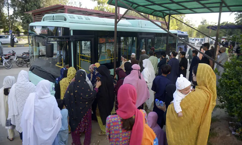 Commuters board an electric bus at the Pims stop in Islamabad on Sunday after public transport, including the metro bus service, resumes after a week-long suspension. &mdash; Photo by Mohammad Asim