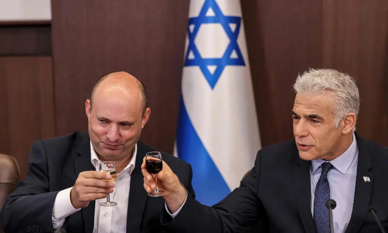 Israel's caretaker Prime Minister Yair Lapid (R) and former prime minister Naftali Bennett toast with small glasses of wine during the weekly cabinet meeting in Jerusalem, on September 18, 2022. &mdash; AFP/File