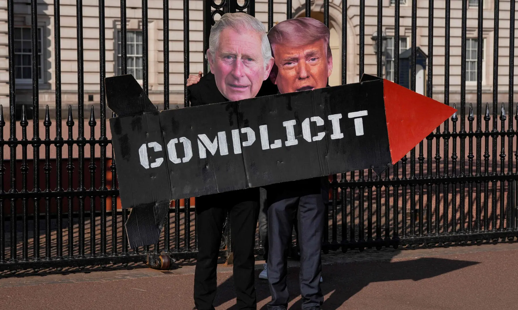 Two members of the 'Stop Trump Coalition' action group pose with a mock missile and masks of Britain's King Charles III and US President Donald Trump in front of the gates of Buckingham Palace in central London on April 27, 2026, to call for an end to the UK's support for the US in the bombing of Iran. &mdash; AFP