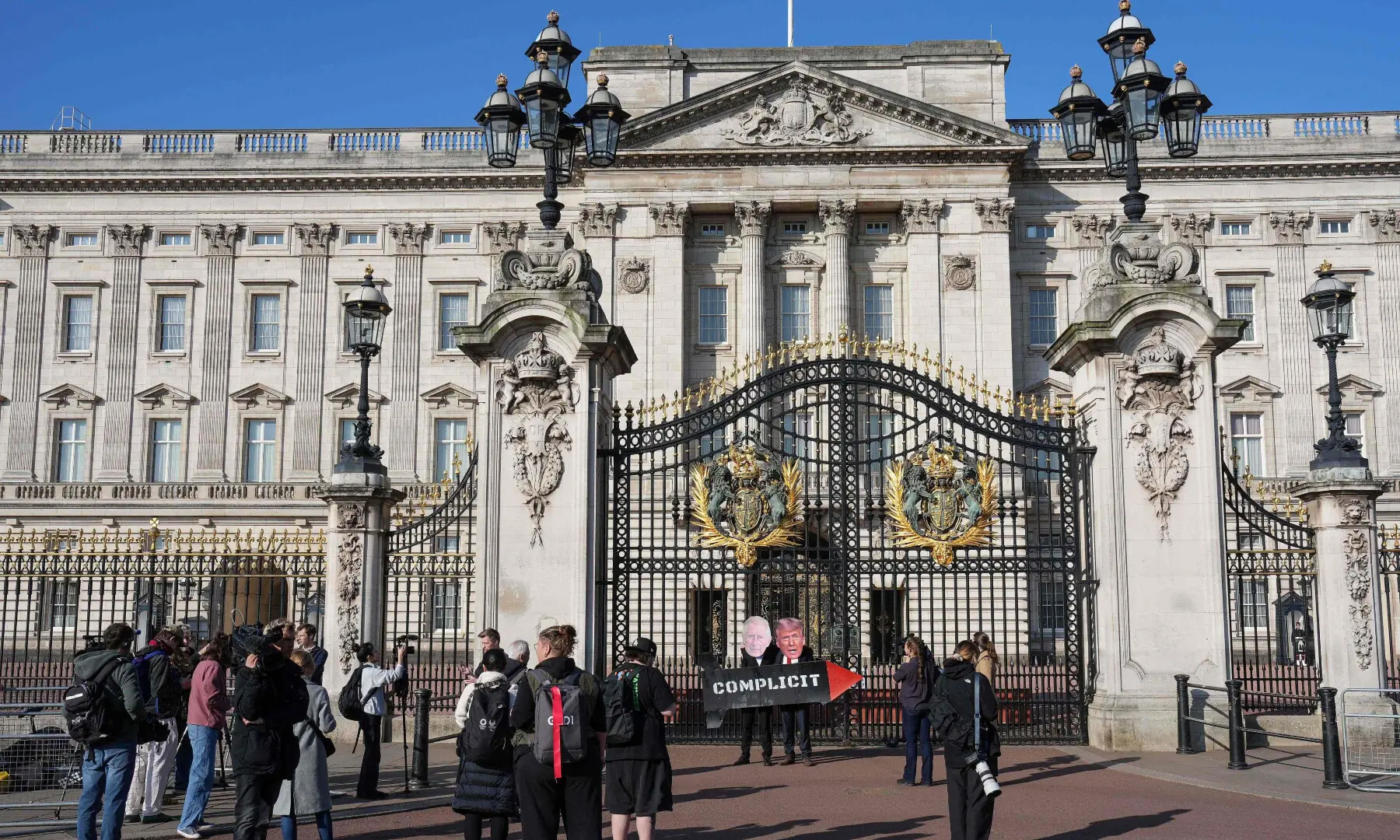 Two members (3rd R) of the 'Stop Trump Coalition' action group pose with a mock missile and masks of Britain's King Charles III and US President Donald Trump in front of the gates of Buckingham Palace in central London on April 27, 2026, to call for an end to the UK's support to the US in the bombing of Iran. &mdash; AFP