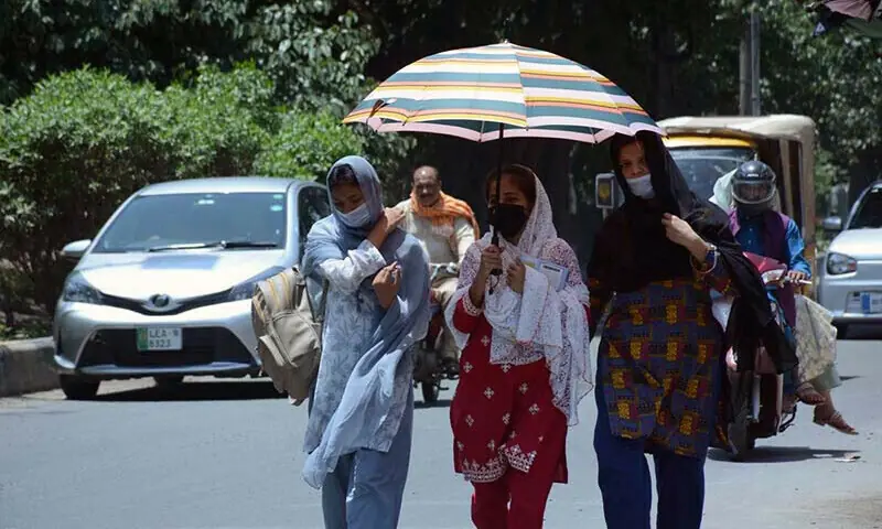 Students use an umbrella to protect themselves from direct sunlight during a hot day in Faisalabad, on May 17, 2024. &mdash;APP/File