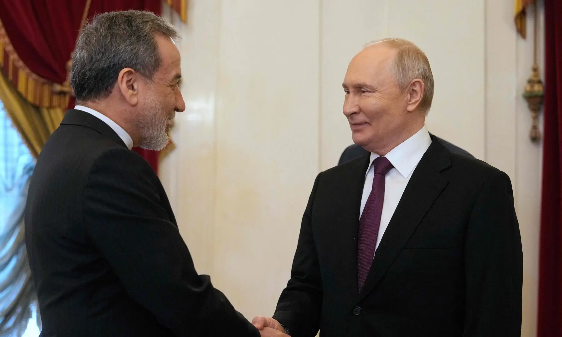 Russian President Vladimir Putin shakes hands with Iranian Foreign Minister Abbas Araghchi during their meeting at the Boris Yeltsin Presidential Library in Saint Petersburg on April 27, 2026. &mdash; AFP