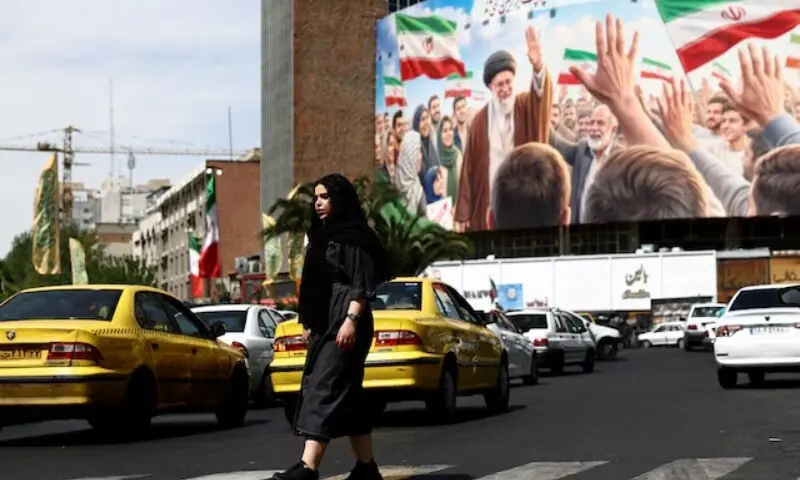 A woman walks past a billboard featuring an image of the late Supreme Leader of Iran, Ayatollah Ali Khamenei, on a building in Tehran, Iran on April 27, 2026. &mdash; Reuters