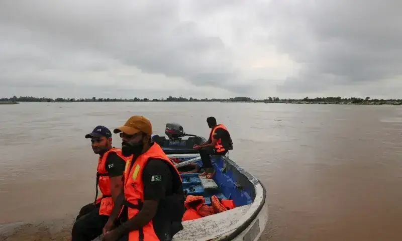 Members of the Rescue 1122 team sit on a boat with the monsoon rain clouds in the background, as they are waiting for residents to evacuate, due to the monsoon rains and rising water level of the Sutlej River, in Ghatti Kalanjar village near the Pakistan-India border in Kasur on August 24. &mdash; Reuters/File