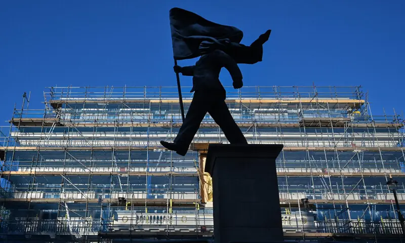 LONODON: A statue of a suited man marching, with one leg off the plinth, while carrying a flag that is covering his face, emerged just off Pall Mall.&mdash;AFP