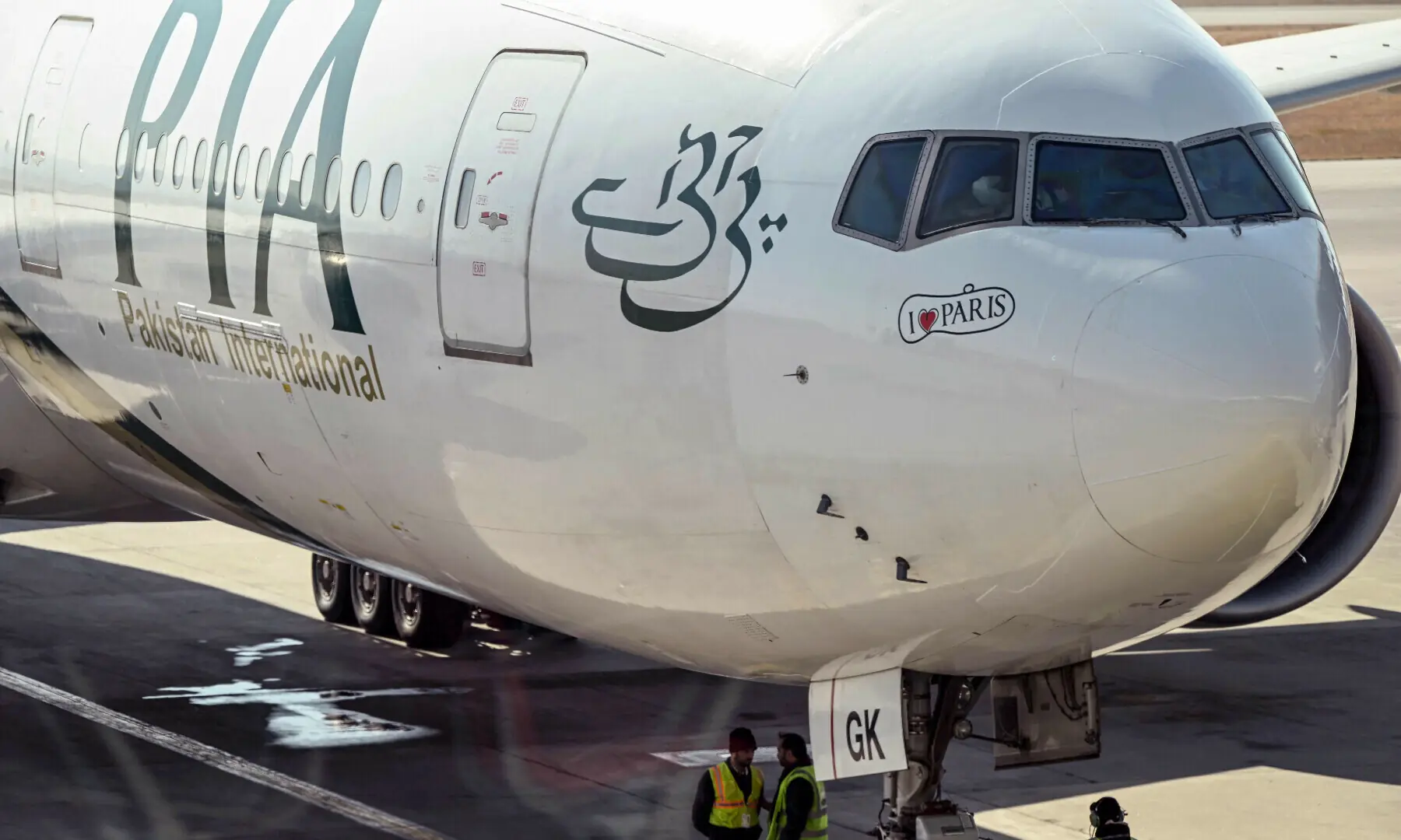 Ground staff stand next to the Pakistan International Airline (PIA) aircraft ahead of its takeoff for Paris at the Islamabad International Airport on Jan 10, 2025. &mdash; AFP