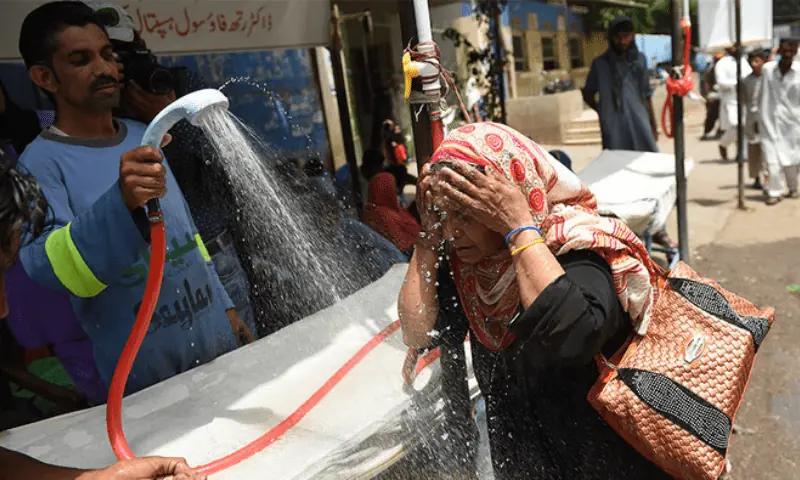 This undated image shows a volunteer showering a woman with water during a heatwave in Karachi. &mdash; AFP/File