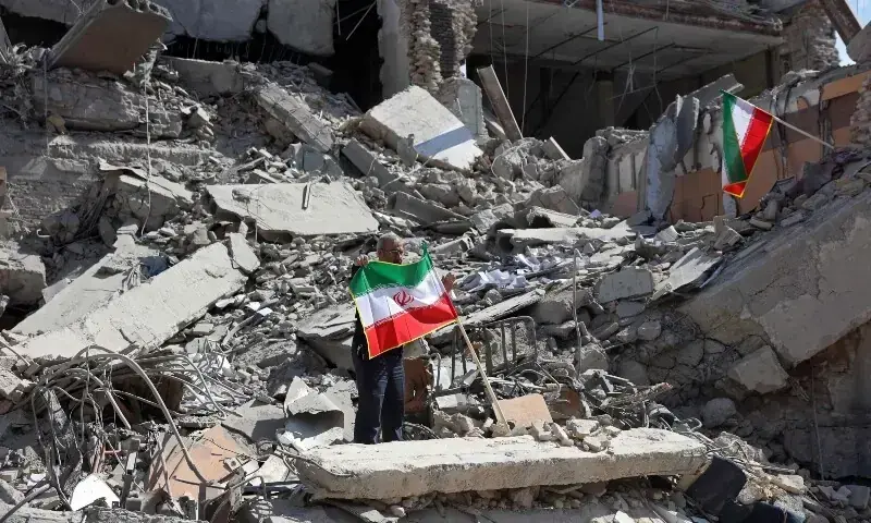 A man holds an Iranian flag amid the debris of a destroyed building following airstrikes in central Tehran, Iran on March 4. &mdash; AFP/ File
