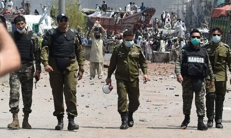 Security personnel walk back after having a talk with supporters of the banned Tehreek-i-Labbaik Pakistan (TLP) during a protest along a blocked street in Lahore in this file photo from April 2021. &mdash; AFP