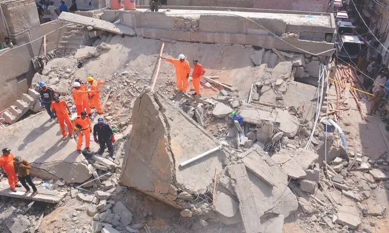 Rescue workers stand amid the rubble of the collapsed building in Shah Faisal Colony on Wednesday.&mdash;Shakil Adil / White Star