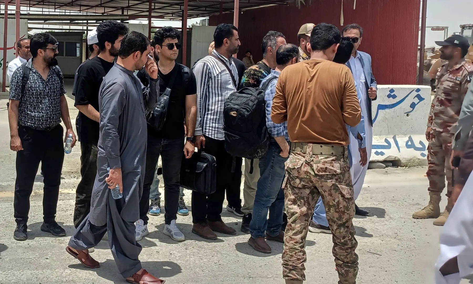 Iranian crew members from a US-seized vessel speak with security officials (R) at Pakistan&rsquo;s Gabd border as they are handed over to Iranian authorities in Gwadar, Balochistan, on May 4, 2026.