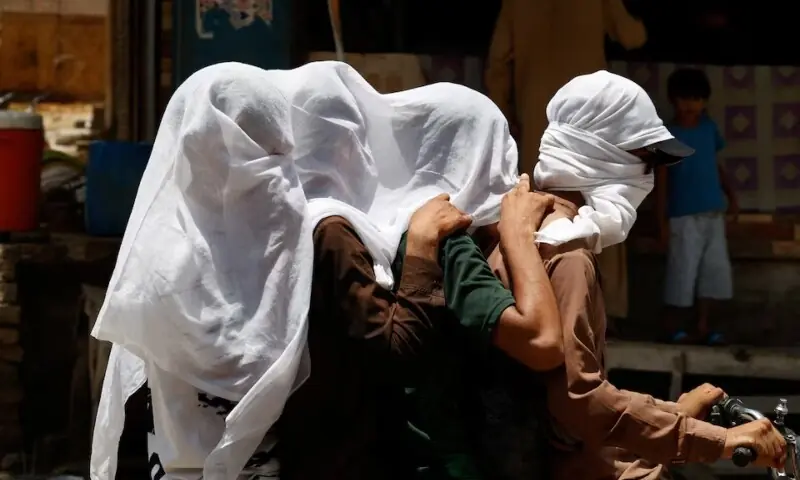 Men ride on a motorbike as they cover their heads with a wet cloth to cool off and to avoid sunlight, during a hot summer day, as the heatwave continues in Jacobabad, Pakistan May 26, 2024. &mdash; Reuters