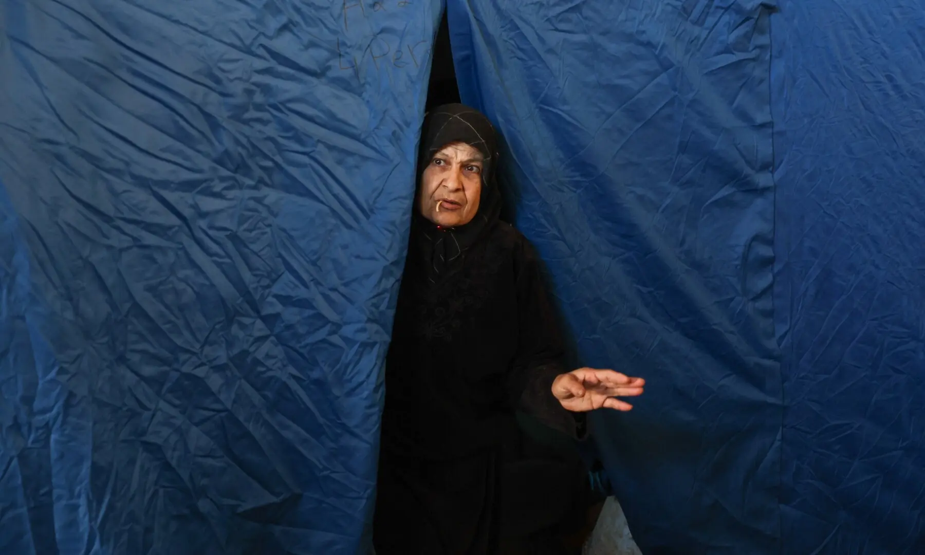 A displaced woman looks out from inside her tent at Camille Chamoun Sports City stadium turned into a temporary shelter in Beirut, Lebanon on May 8, 2026. &mdash;Reuters