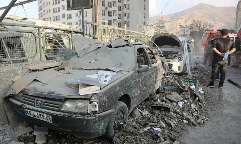 People gather near damaged vehicles in the aftermath of Israeli strikes, in Tehran, Iran, March 3. &mdash; Reuters/File