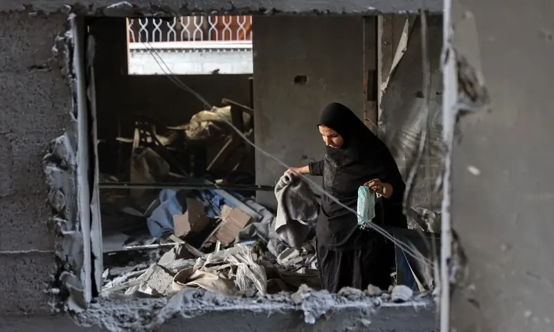 A Palestinian woman looks for her belongings inside a damaged building, a day after of an Israeli strike at the Shati refugee camp (Beach) in Gaza City, on May 9, 2026. &mdash;AFP