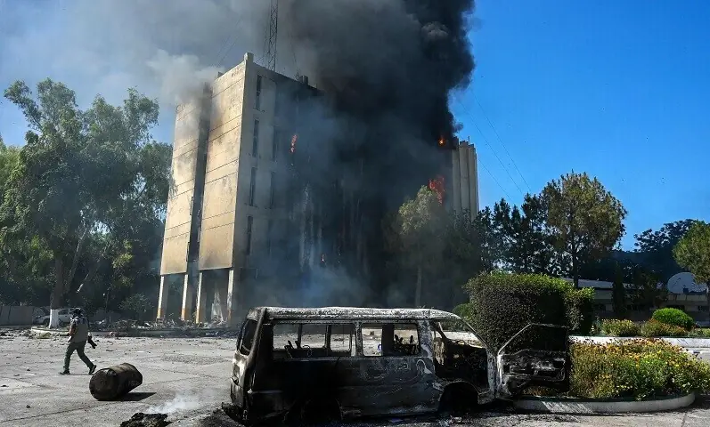 Black smokes billows from a building set ablaze by PTI activists and supporters of former prime minister Imran Khan during a protest against the arrest of their leader, in Peshawar on May 9, 2023. &mdash; AFP/File