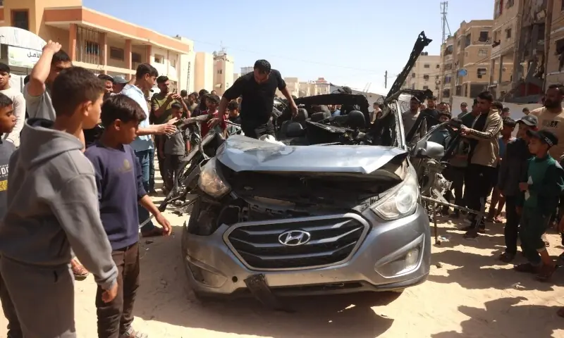 Palestinians gather as they inspect the remains of a vehicle destroyed in an Israeli strike in Khan Yunis, in the southern Gaza Strip, on May 10, 2026. &mdash; AFP