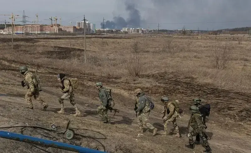 In this file photo, Ukrainian servicemen walk near a destroyed bridge in the town of Irpin outside Kyiv, Ukraine. &mdash; Reuters/File