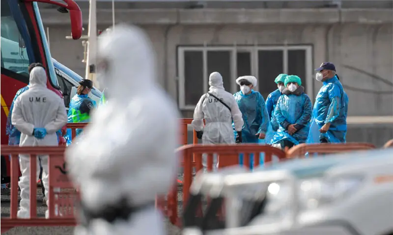 Passengers wearing blue protective suits board a military bus after being evacuated from MV Hondius at industrial port of Granadilla de Abona.&mdash;AFP