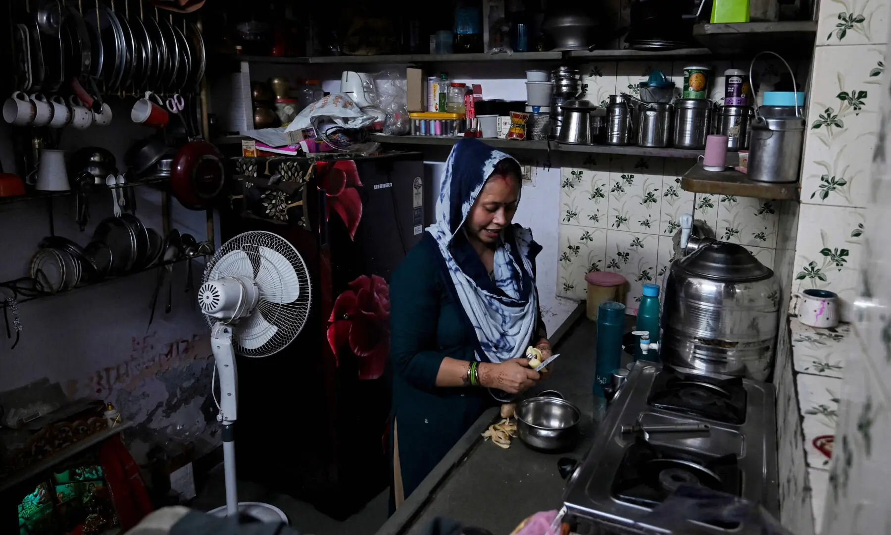 This photograph taken on April 28, 2026 shows Rakhi Gulshan Singh, a seamstress and policyholder of a heat insurance scheme, preparing a meal inside her single-room rented house in Ahmedabad. — AFP