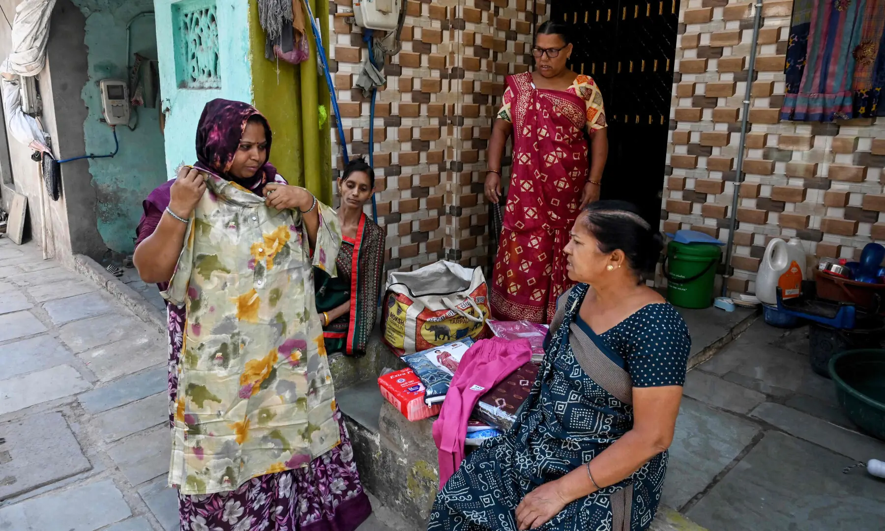 This photograph taken on April 28, 2026 shows Lata Solanki (L), a clothes seller and policyholder of a heat insurance scheme, conducting a door-to-door sales in Ahmedabad. — AFP