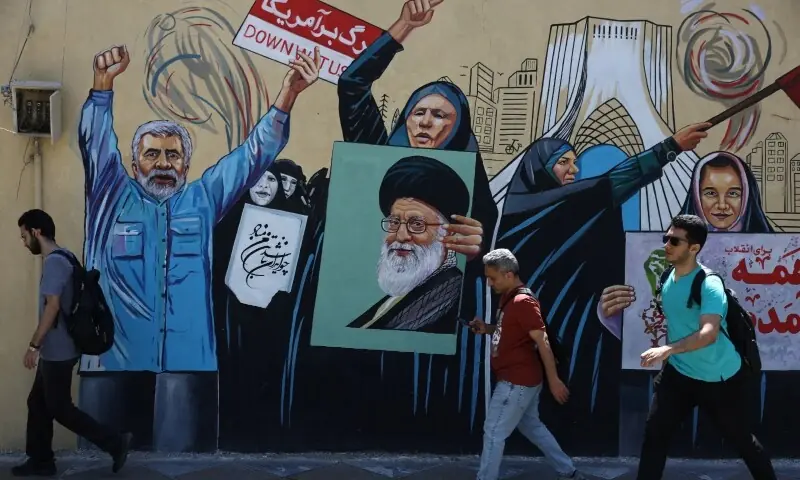 People walk on a street near a mural featuring an image of the late Supreme Leader of Iran, Ayatollah Ali Khamenei, in Tehran, Iran, May 11, 2026. &mdash; Reuters