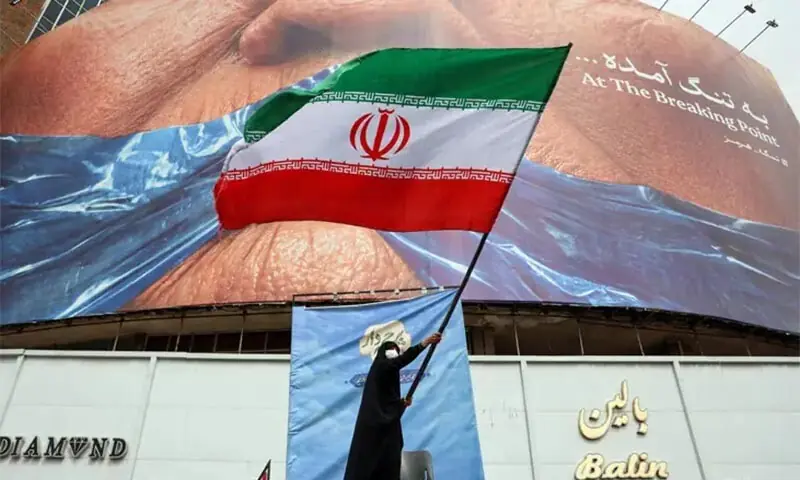 A woman waves an Iranian flag in front of an anti-US billboard in Valiasr Square, in Tehran, Iran on May 6, 2026. &mdash; AFP