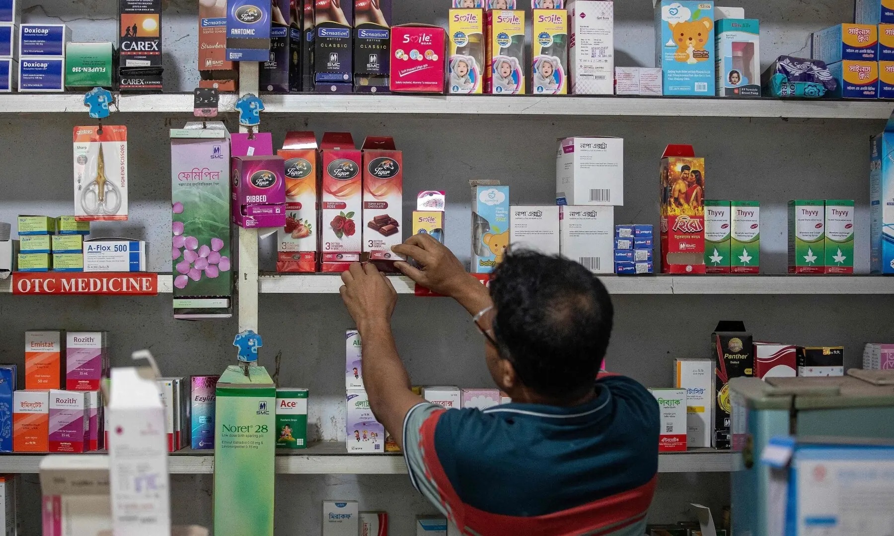 This photograph taken on April 27, 2026 shows a worker arranging packets of condoms at a pharmacy in Dhaka. &mdash;AFP