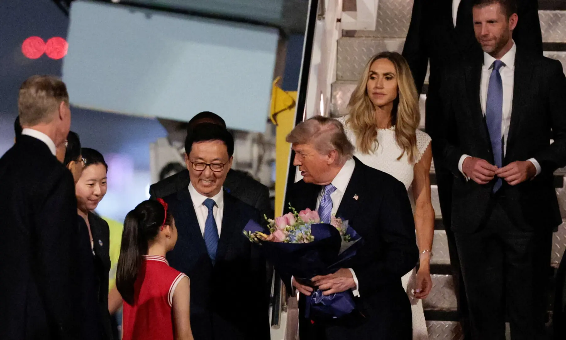 US President Donald Trump receives flowers, next to Chinese Vice President Han Zheng, Eric Trump and his wife Lara, during an arrival ceremony at Beijing Capital International Airport, in Beijing, China on May 13, 2026. &mdash; Reuters