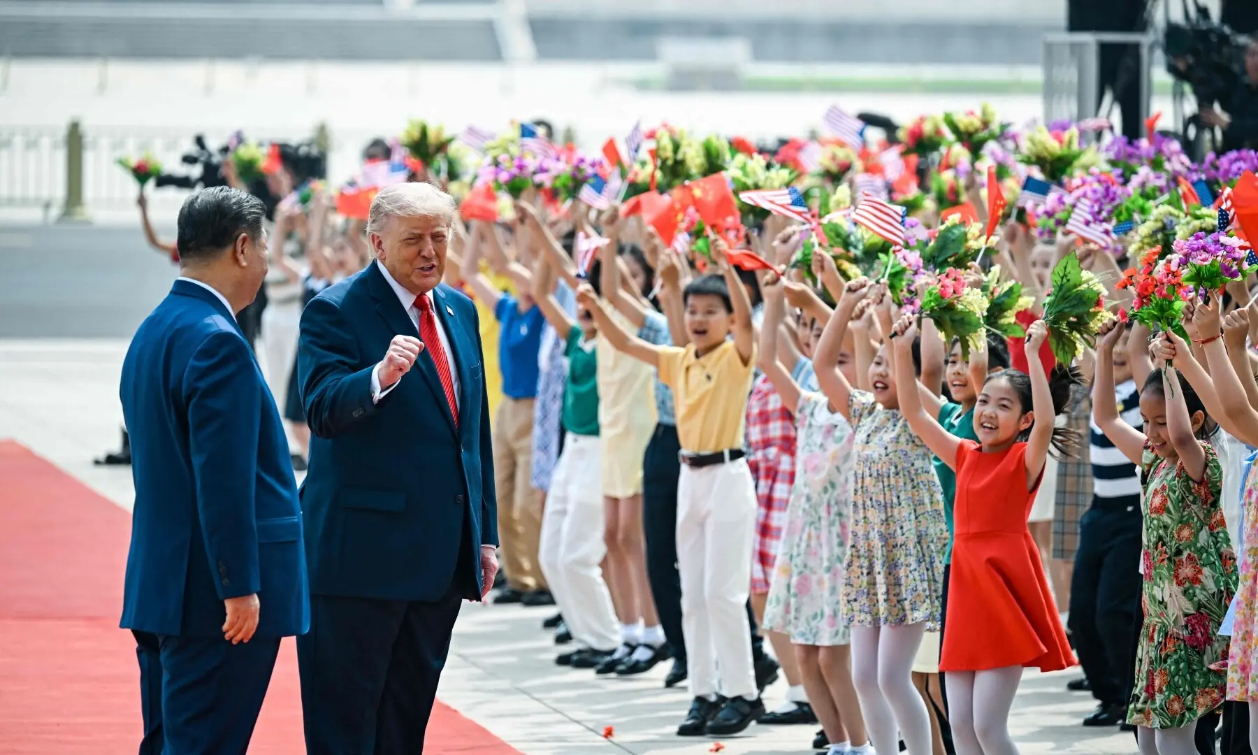 US President Donald Trump (R) and China&rsquo;s President Xi Jinping (L) greet children waving Chinese and US national flags and flowers during a welcome ceremony at the Great Hall of the People in Beijing on May 14, 2026. &mdash;AFP